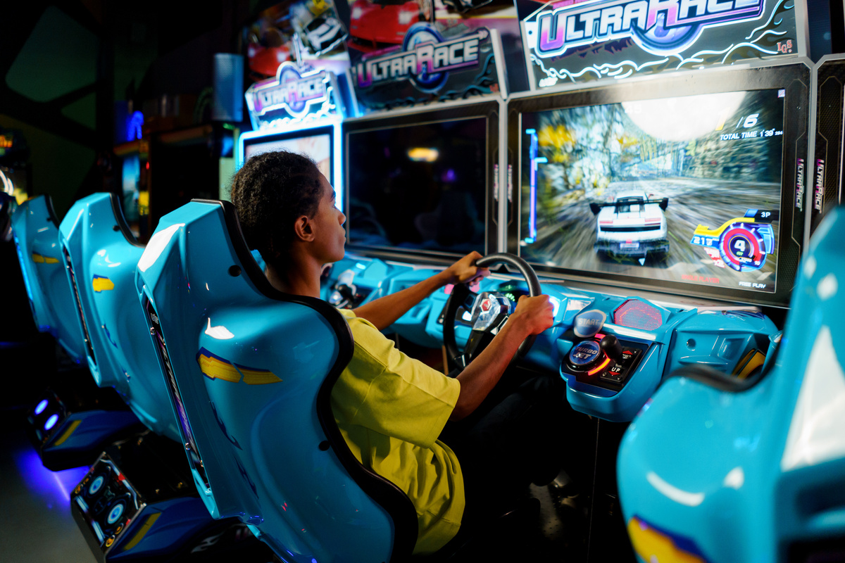 Man in Yellow Shirt Riding Blue and Yellow Arcade Game